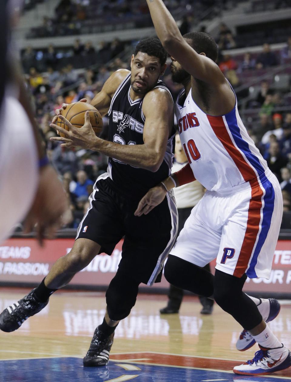 San Antonio Spurs forward Tim Duncan (21) drives on Detroit Pistons forward Greg Monroe (10) during the first half of an NBA basketball game in Auburn Hills, Mich., Monday, Feb. 10, 2014. (AP Photo/Carlos Osorio)