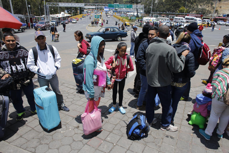 En esta imagen, tomada el 5 de septiembre de 2018, la venezolana Sandra Cádiz y su hija Angelis, de 10 años, esperan en una fila con otros migrantes para pasar un control en Ipiales, Colombia, antes de cruzar el puente internacional Rumichaca (detrás de ellos) a Ecuador. (AP Foto/Ariana Cubillos)