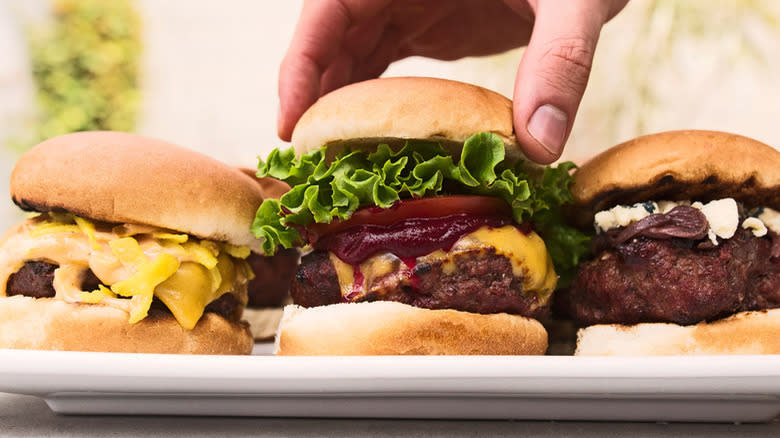hand placing top bun onto burger
