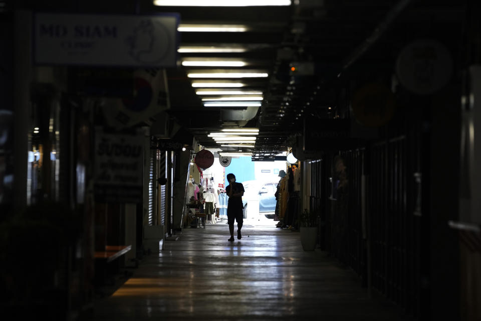 A person walks through closed shops in Siam Square, a famous shopping district in Bangkok, Thailand on Aug. 3, 2021. As Thailand battles a punishing COVID-19 surge with nearly 20,000 new cases every day, people who depend on tourism struggle in what was one of the most-visited cities in the world, with 20 million visitors in the year before the pandemic. (AP Photo/Sakchai Lalit)