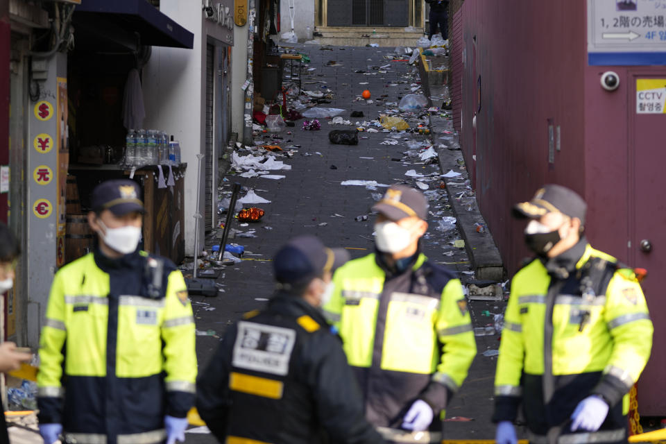 South Korean police officers stand guard at the scene in Seoul, South Korea, Sunday, Oct. 30, 2022. A mass of mostly young people celebrating Halloween festivities in Seoul became trapped and crushed as the crowd surged into a narrow alley, killing dozens of people and injuring dozens of others in South Korea's worst disaster in years. (AP Photo/Lee Jin-man)