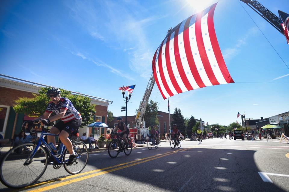 Bikers ride through underneath a huge American flag during a parade in Ridgewood, N.J., on July 4, 2022.
