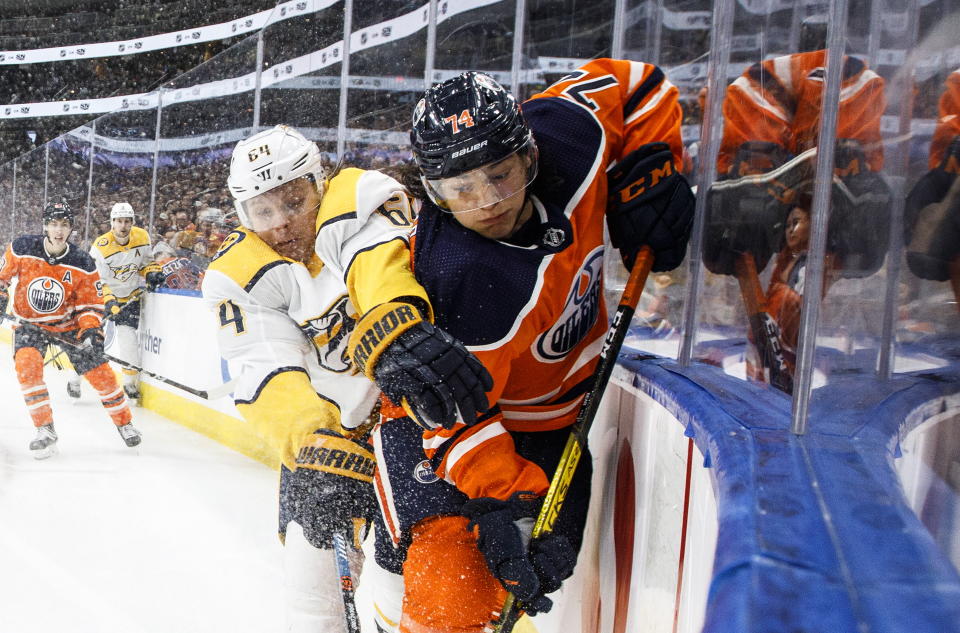 Nashville Predators' Mikael Granlund (64) and Edmonton Oilers' Ethan Bear (74) battle for the puck during third-period NHL hockey game action in Edmonton, Alberta, Saturday, Feb. 8, 2020. (Jason Franson/The Canadian Press via AP)