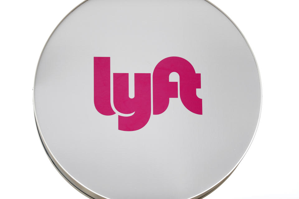 FILE - In this March 24, 2020, file photo, a Lyft sign is shown at a ride-hailing pickup location for automobiles in Detroit. Toyota Motor Corp. has acquired the self-driving division of American ride-hailing company Lyft for $500 million, in a move that underlines the Japanese automaker’s ambitions in that technology, announced Tuesday, April 27, 2021. (AP Photo/Paul Sancya, File)