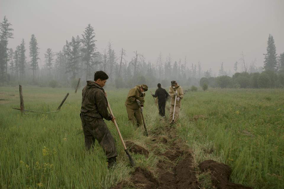 Member of volunteers crew dig a fire-break moat to stop the fire from spreading at Gorny Ulus area west of Yakutsk, Russia, Tuesday, July 20, 2021. The hardest hit area is the Sakha Republic, also known as Yakutia, in the far northeast of Russia, about 5,000 kilometers (3,200 miles) from Moscow. About 85% of all of Russia's fires are in the republic, and heavy smoke forced a temporary closure of the airport in the regional capital of Yakutsk, a city of about 280,000 people. (AP Photo/Ivan Nikiforov)