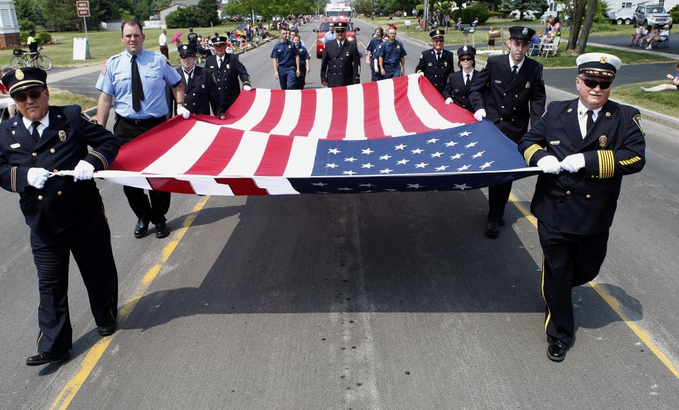 Members of the North Greece Fire Department carry a large American flag in the Greece Memorial Day Parade in 2014.