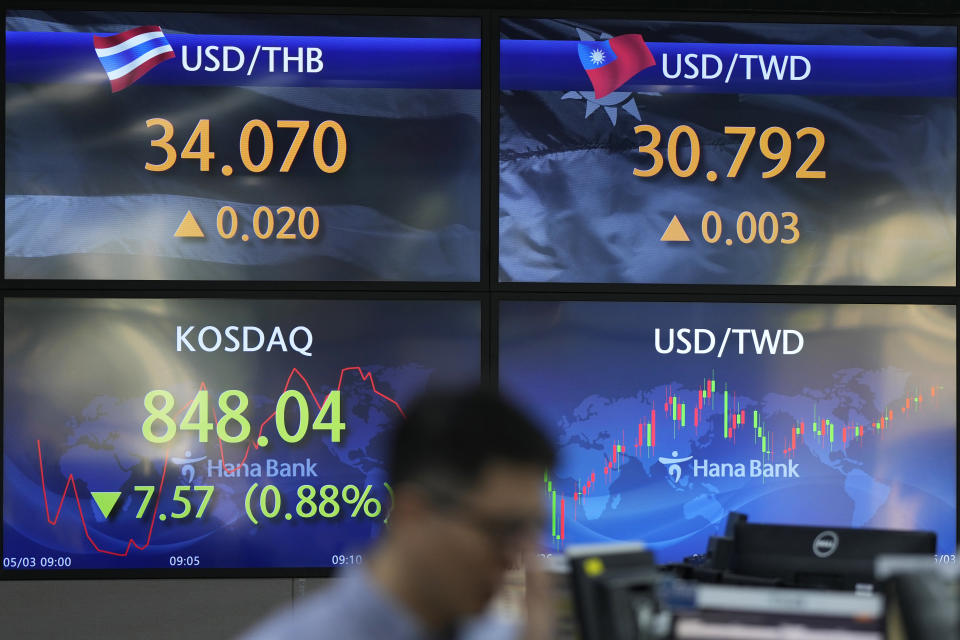 A currency trader walks near the screens showing the Korean Securities Dealers Automated Quotations (KOSDAQ), and the foreign exchange rates at a foreign exchange dealing room in Seoul, South Korea, Wednesday, May 3, 2023. Asian shares declined Wednesday, tracking losses on Wall Street as shares of beleaguered banks tumbled again and worries about the economy deepened. (AP Photo/Lee Jin-man)