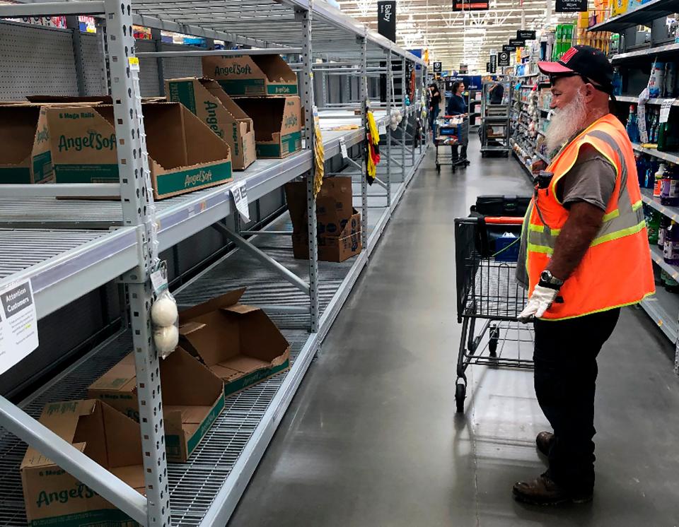 A shopper looks at a cleaned-out toilet paper aisle in a Phoenix Walmart, March 20. (ASSOCIATED PRESS)