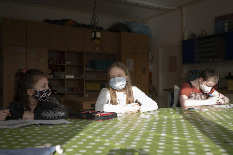 Nine-year-old girl Pollina Dinner, center, sits between other children in a schoolwork room at the Arche, or Ark, an organization that supports children, youth and families in the Hellersdorf neighbourhood, on the eastern outskirts of Berlin, Germany, Tuesday, Feb. 23, 2021. After two months of lockdown, Pollina Dinner went back to school for the first time on Monday, Feb. 22. Since the outbreak of the coronavirus pandemic, the Arche has had to reduce their real face-to-face assistance or traditional classroom schooling as an offer for children, mainly from underprivileged families, drastically. Some kids are still allowed to come over in person, but only once every two weeks. (AP Photo/Markus Schreiber)