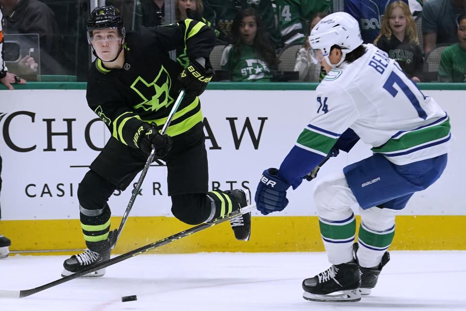 Dallas Stars defenseman Nils Lundkvist (5) moves the puck past Vancouver Canucks defenseman Ethan Bear (74) during the first period of an NHL hockey game in Dallas, Saturday, March 25, 2023. (AP Photo/LM Otero)
