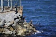 A Spanish Guardia Civil officer stands next to a group of men from Morocco who are trying to cross into the Spanish territory at the border with the Spanish enclave of Ceuta on Monday, May 17, 2021. Authorities in Spain say that around 1,000 Moroccan migrants have crossed into Spanish territory (Antonio Sempere/Europa Press via AP)