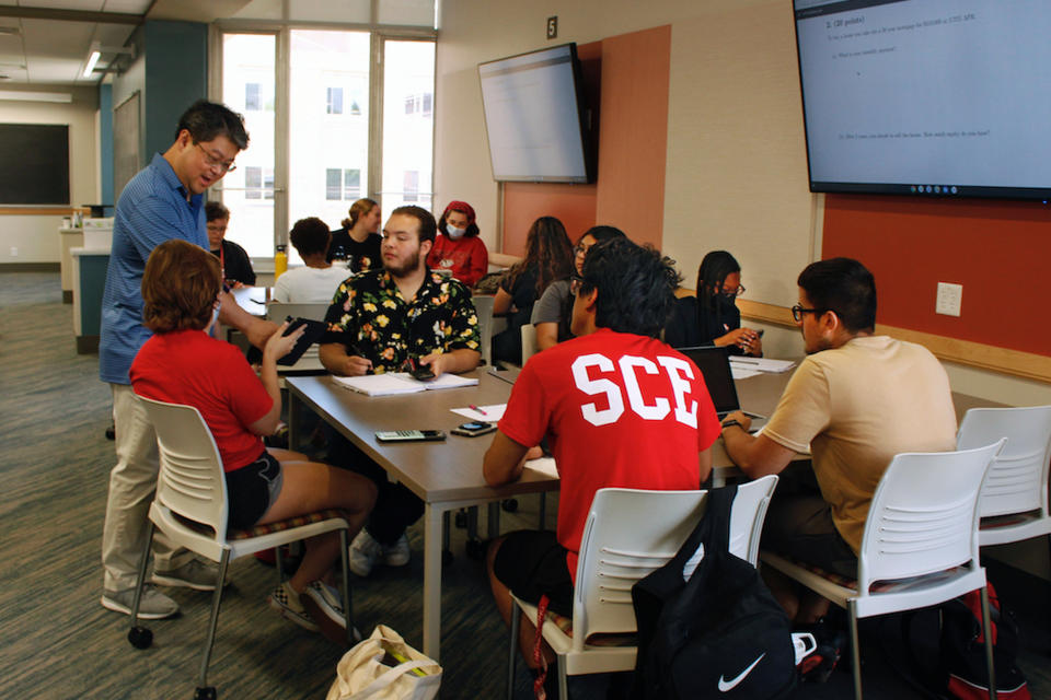 Instructor Oh Moon Kwon, left, speaks to students during a math class, part of an intense six-week summer bridge program for students of color and first-generation students at the University of Wisconsin, in Madison, Wis., July 27, 2022. Seated, in the flowered black shirt is Angel Hope, who said he didn't feel ready for college after online classes in high school caused him fall behind, but says the bridge classes made him feel more confident. Hundreds of thousands of recent graduates are heading to college this fall after spending more than half their high school careers dealing with the upheaval of a pandemic. (AP Photo/Carrie Antlfinger)