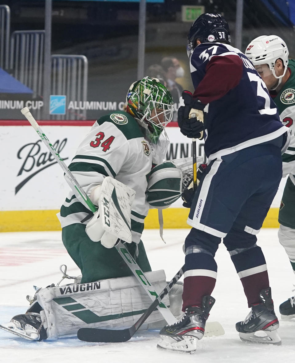 Minnesota Wild goaltender Kaapo Kahkonen, left, makes a stop of a shot off the stick of Colorado Avalanche left wing J.T. Compher in the first period of an NHL hockey game Wednesday, Feb. 24, 2021, in Denver. (AP Photo/David Zalubowski)