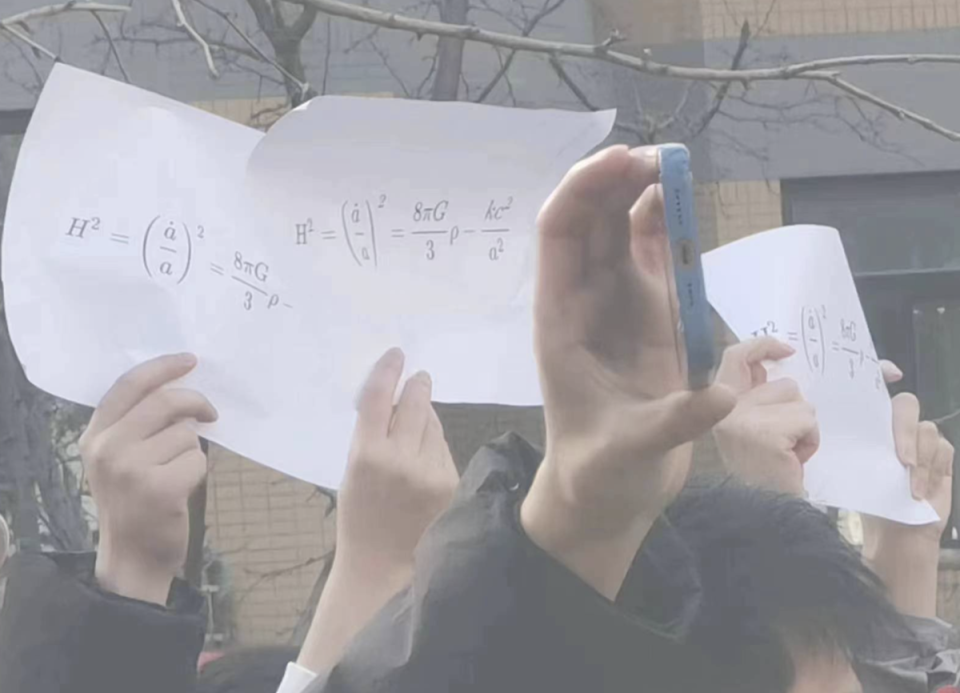新疆烏魯木齊惡火釀10死，使各地不滿情緒暴漲，其中北京清華大學學生舉著寫有方程式的白色A4紙，背後藏抗議訴求。（翻攝羅冠聰推特）