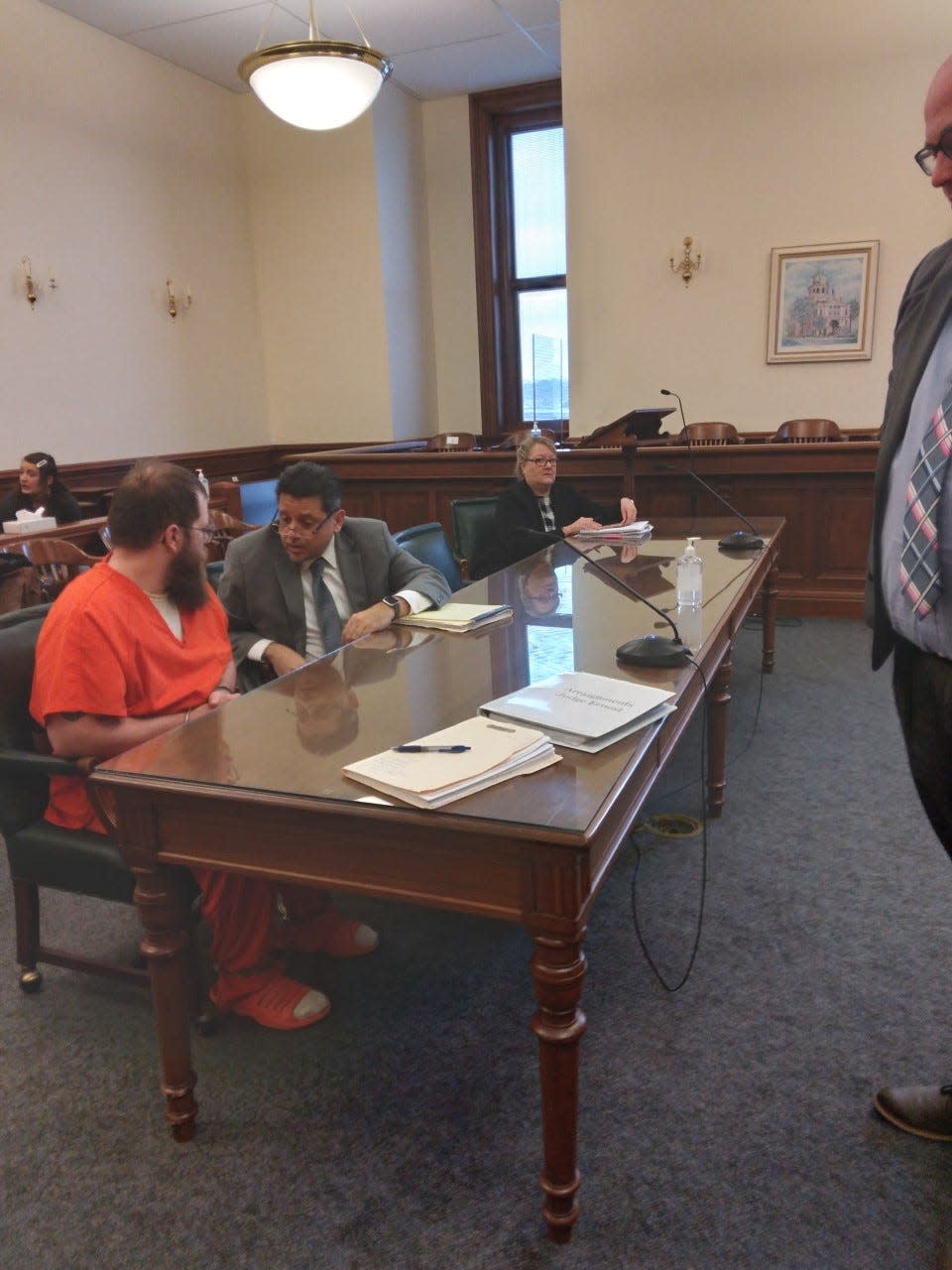 Clifford L. Sutton Jr., in orange, awaits transportation to begin serving a life sentence for child rape. He is speaking with defense attorney Anthony Koukoutas in Tuscarawas County Common Pleas Court on Friday, when he was sentenced by Judge Michael J. Ernest.