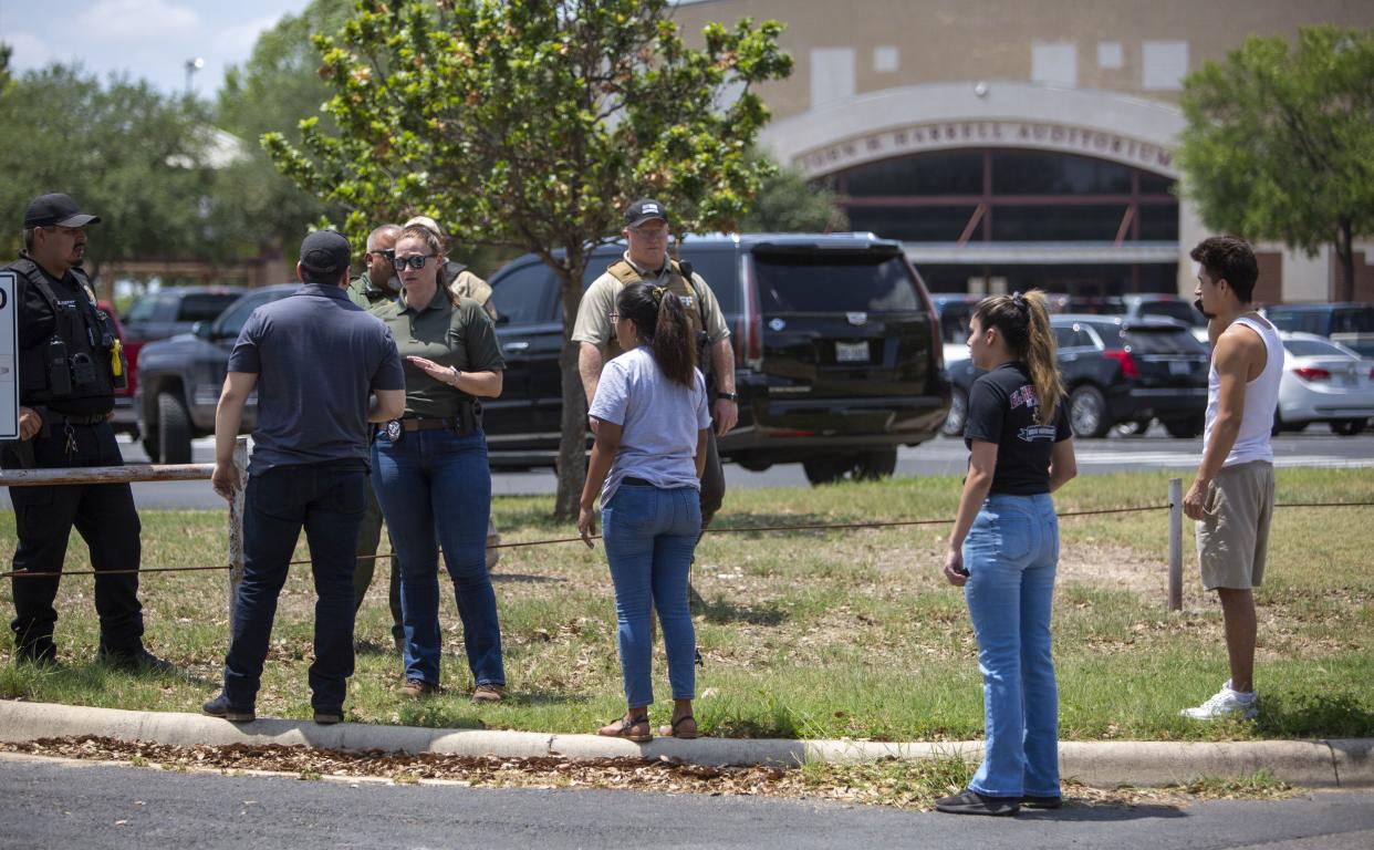 A law enforcement officer speaks with people outside Uvalde High School after shooting a was reported earlier in the day at Robb Elementary School, Tuesday, May 24, 2022, in Uvalde, Texas. 