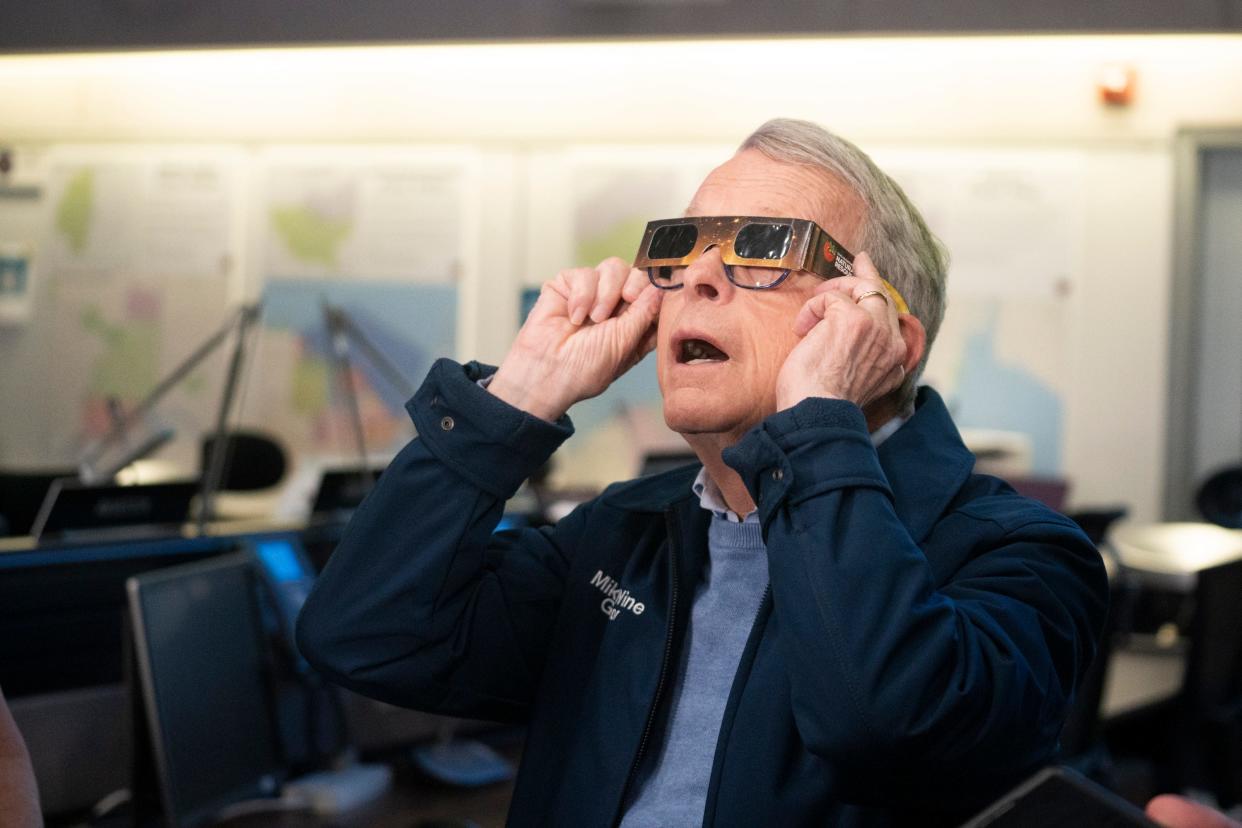 Gov. Mike DeWine demonstrates how to wear eclipse glasses during a news conference at the Ohio Emergency Operations Center in Columbus on Friday.