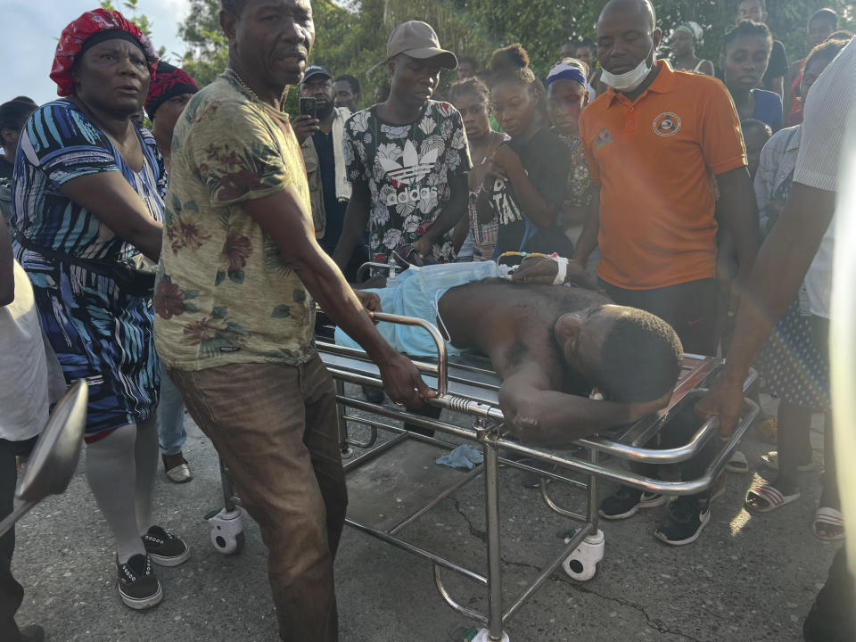 People transport an injured person after rescuing him from a house that collapse after an earthquake in Jeremie, Haiti, Tuesday, June 6, 2023. (AP Photo/Ralph Simon)