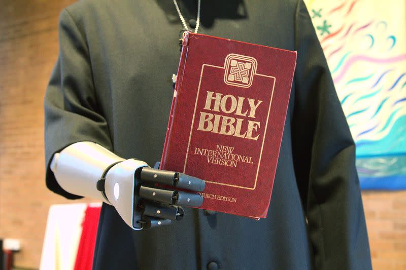 Priest-in-training Daniel Cant holds a bible as he demonstrates his bionic arm by British company Open Bionics at Christ Church in Colchester