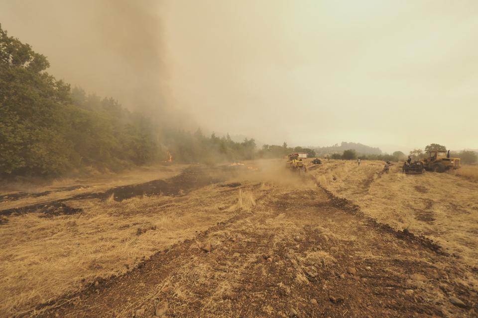 Bulldozers open fire break at a forest during a wildfire near Kechries village on the island of Evia, about 144 kilometers (90 miles) north of Athens, Greece, Thursday, Aug. 5, 2021. Forest fires fueled by a protracted heat wave raged overnight and into Thursday in Greece, threatening the archaeological site at the birthplace of the modern Olympics and forcing the evacuation of dozens of villages. (AP Photo/Thodoris Nikolaou)