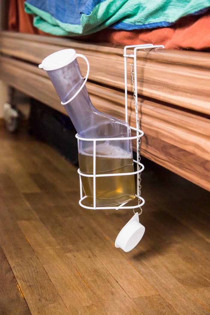 Homemade under-bed beer dispenser with a plastic funnel and tubing attached to a cup holder