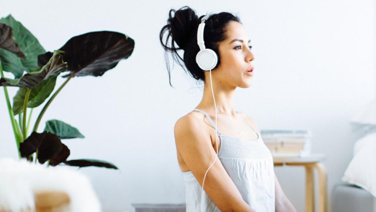 Psych Study Finds 10 Minutes of Daily Meditation Can Lower Anxiety: woman meditating with headphones