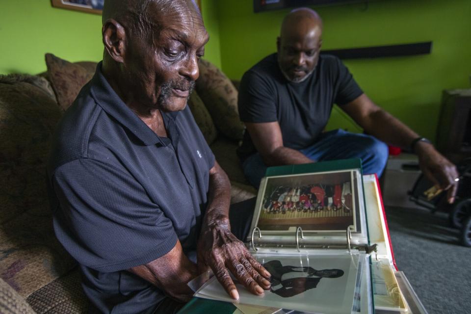 Robert Meeks Jr. and his son, Robert Meeks, look over family photos.