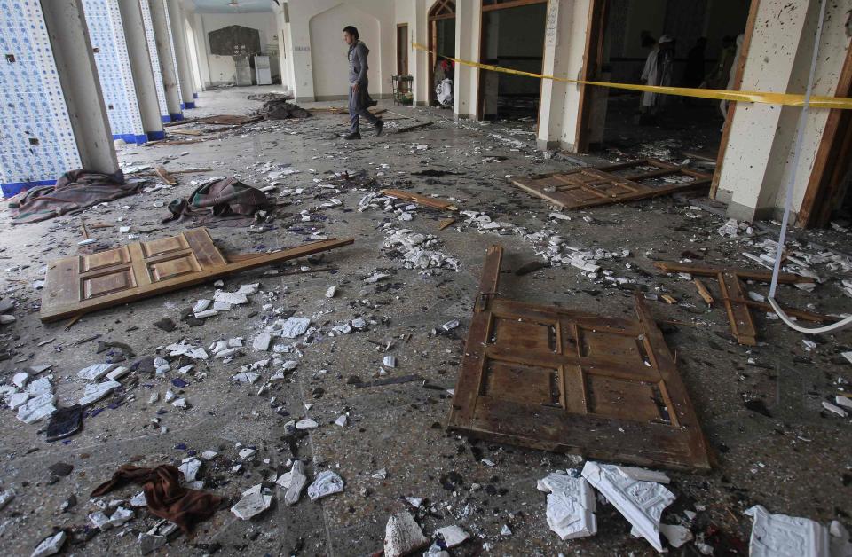 A man walks past broken glass and doors after an explosion in a Shi'ite mosque in Peshawar