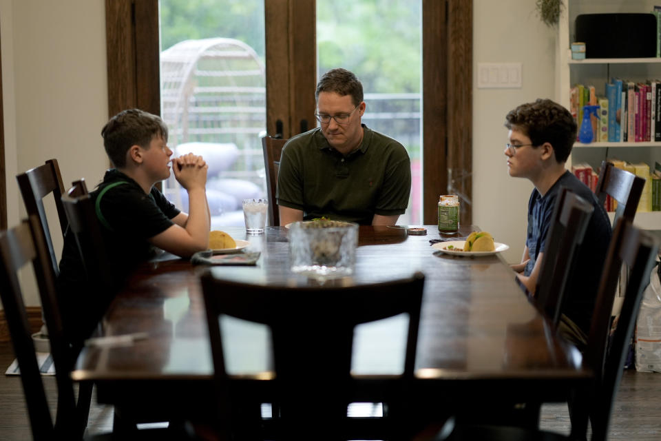 Nicholas Parrott-Sheffer, 12, left, prays for dinner with his father Adam and his 14 year-old brother Nathan at their home in the Hyde Park neighborhood of Chicago, Tuesday, May 21, 2024. The nation's third-largest city is preparing for its first-ever school board elections and the slate of potential candidates include progressive activists, an afterschool squash program leader and a Grammy-winning rapper. (AP Photo/Charles Rex Arbogast)