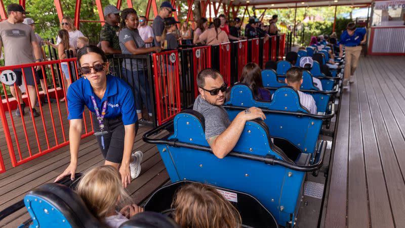 Yelitza R. checks safety restraints on a roller coaster at Lagoon in Farmington on Aug. 5, 2022. Lagoon’s opening day for 2023 was postponed to April 1 because of inclement weather.