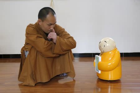 Master Xianfan looks at robot monk Xian'er as he demonstrates the robot's conversation function during a photo opportunity in Longquan Buddhist temple on the outskirts of Beijing, April 20, 2016. REUTERS/Kim Kyung-Hoon