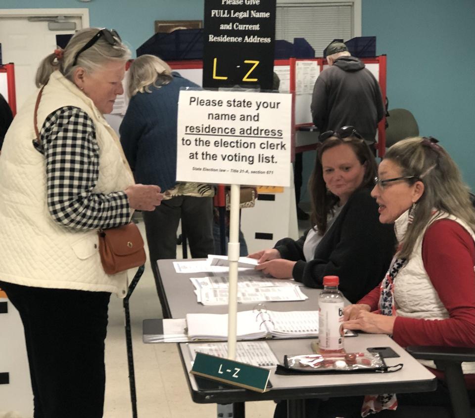 Voter Linda Ruskoski gets her ballot from election clerks Jamie Mitchell, center, and Karen Schlegel, right, at the Village Fire Station during the special town meeting in Kennebunkport, Maine, on Tuesday, Nov. 7, 2023.