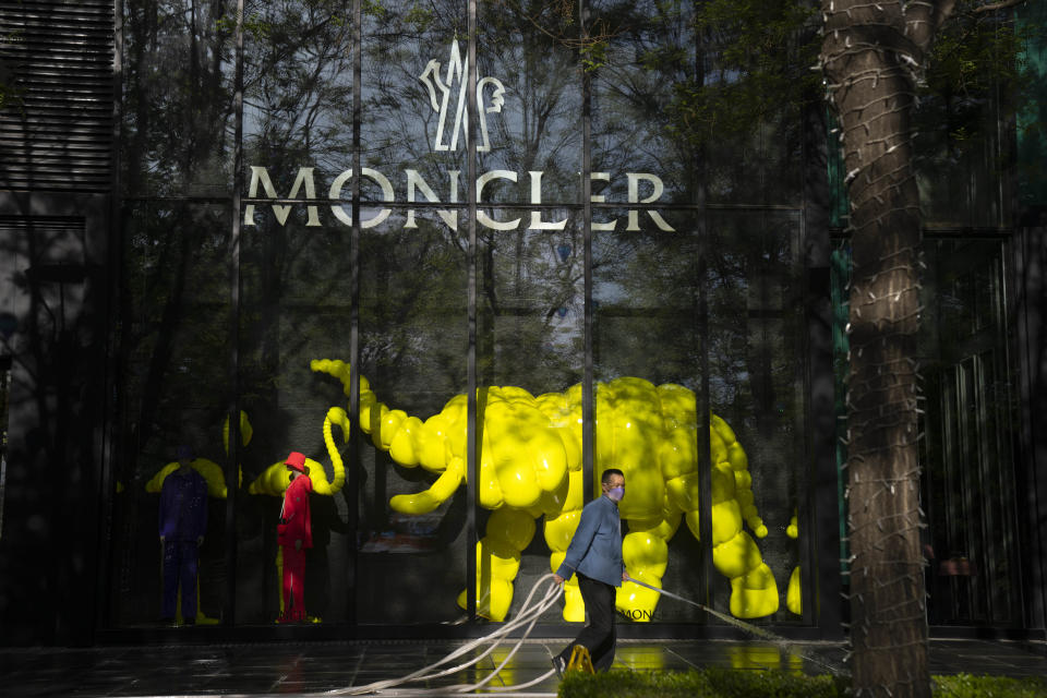 A worker sprays down the sidewalk outside of an outlet of Italian fashion retailer Moncler at a shopping mall in Beijing, on April 18, 2023. Foreign companies are shifting investments and their Asian headquarters out of China as confidence plunges following the expansion of an anti-spying law and other challenges, the European Union Chamber of Commerce in China said Wednesday, June 21, 2023. (AP Photo/Mark Schiefelbein)