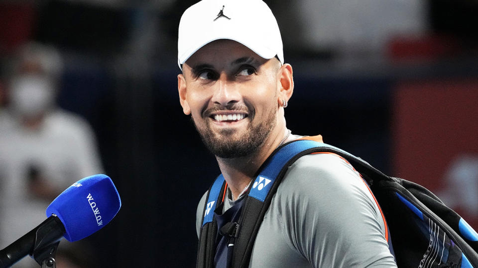 Nick Kyrgios smiles during an on-court interview.