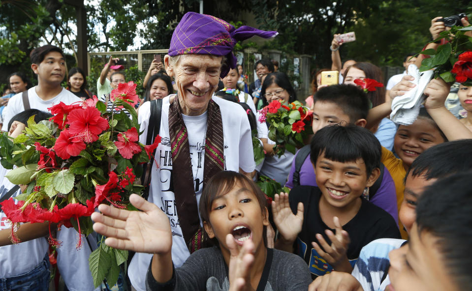Australian Roman Catholic nun Sister Patricia Fox receives flowers from children of informal settlers as she arrives for a visit to the Redemptorist Church prior to her departure for Australia Saturday, Nov. 3, 2018 in suburban Paranaque city, south of Manila, Philippines. Sister Fox decided to leave after 27 years in the country after the Immigration Bureau denied her application for the extension of her visa. The Philippine immigration bureau has ordered the deportation of Fox who has angered the president by joining anti-government rallies. (AP Photo/Bullit Marquez)