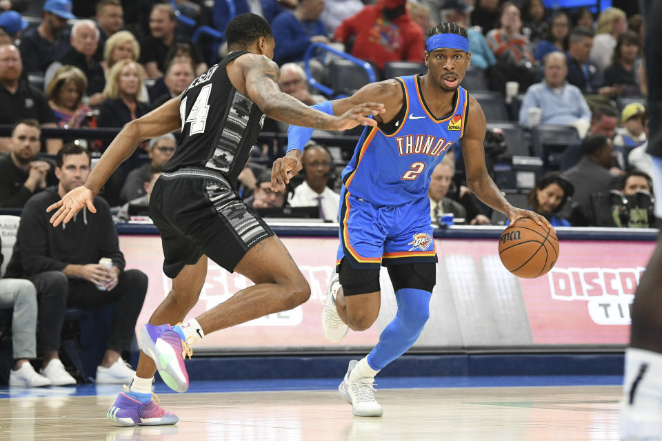 Oklahoma City Thunder guard Shai Gilgeous-Alexander, right, drives past San Antonio Spurs guard Devin Vassell during the first half of an NBA basketball game Wednesday, April 10, 2024, in Oklahoma City. (AP Photo/Kyle Phillips)