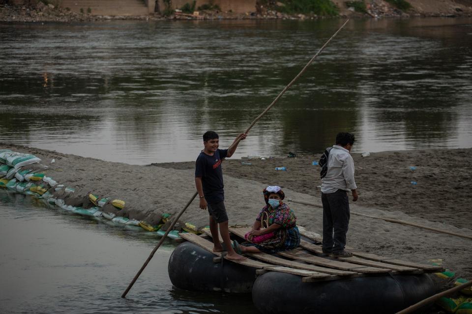 A kid working as a rafter crosses a Guatemalan woman from the Mexican side of the Suchiate River.