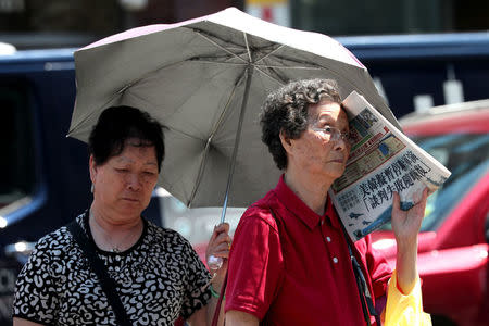 People shelter themselves from the sun in the Chinatown section of Manhattan during hot weather in New York City, New York, U.S., June 18, 2018. REUTERS/Mike Segar