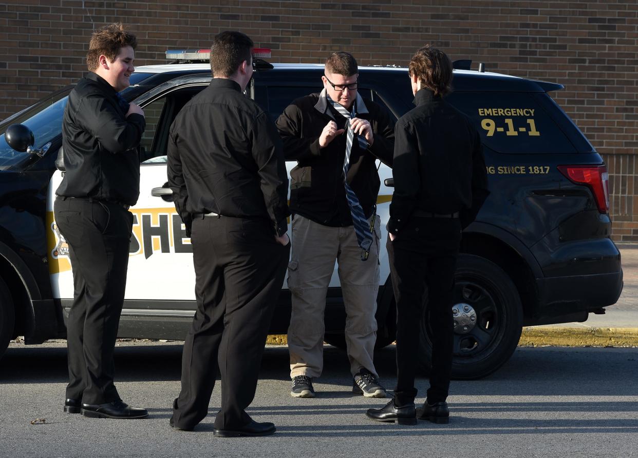 Monroe County Sheriff Deputy Ryan Sottile, who serves as the school resource officer (SRO) at Airport High School, helps junior Aiden Self (right) tie his tie prior to the school's coming home dance last March. Self's friends Chase Johnson and Wade Cline look on. Airport is adding a second SRO for the 2022-'23 school year.