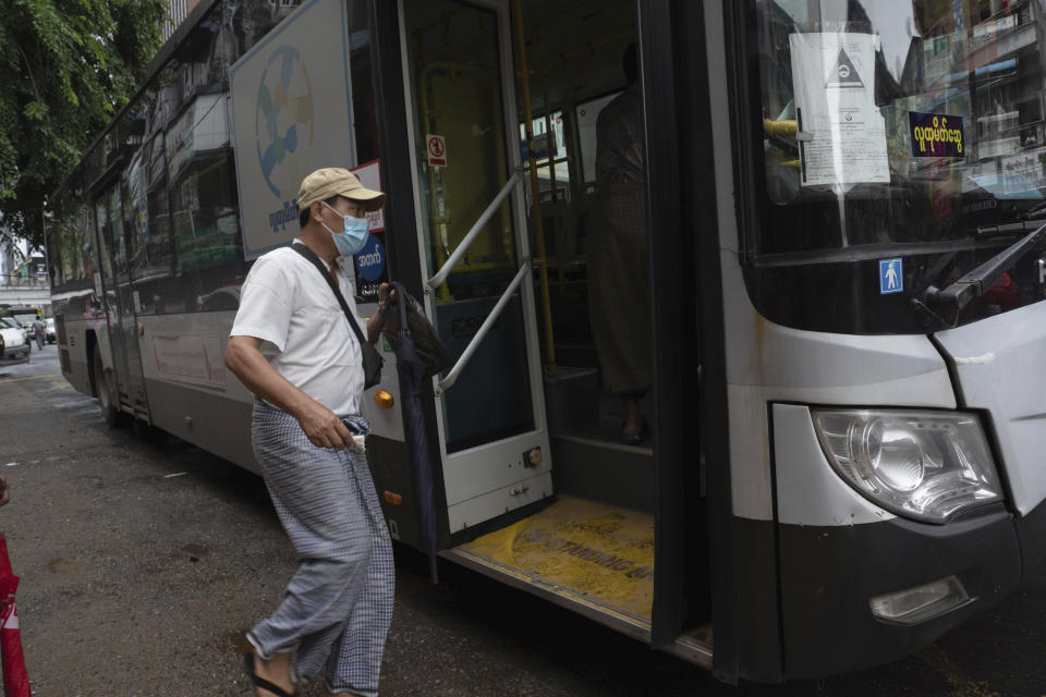 A commuter wearing a face mask boards a bus in Yangon, Myanmar,Monday, Sept. 21, 2020. Myanmar, faced with a rapidly rising number of coronavirus cases and deaths, has imposed the tightest restrictions so far to fight the spread of the disease in Yangon, the country's biggest city and main transportation hub. (AP Photo/Pyae Sone Win)