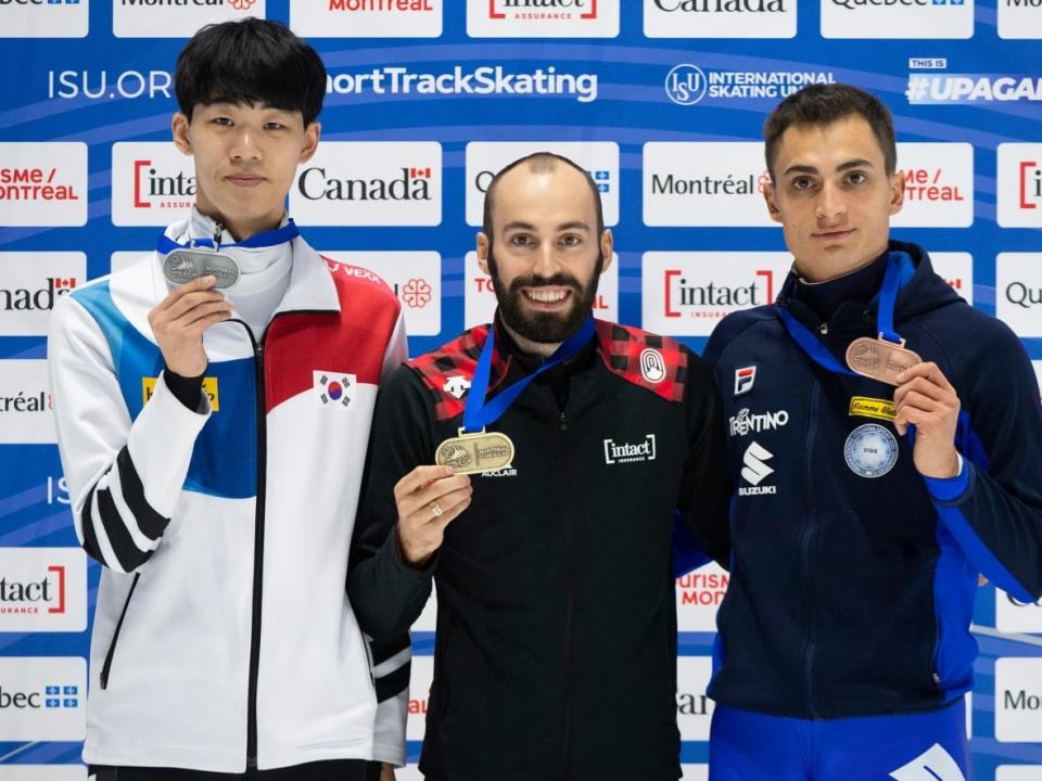 Steven Dubois of Canada, centre, holds up his gold medal alongside silver medallist Lee June-Seo of South Korea, left, and bronze-medallist Pietro Sighel of Italy following the men's 500-metre final at the ISU World Cup short track speed skating event in Montreal. (Graham Hughes/The Canadian Press - image credit)