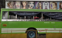 Passengers wearing face masks sit inside a bus as it halts before a beauty salon during the coronavirus pandemic in Kochi, Kerala state, India, Monday, June 1, 2020. More states opened up and crowds of commuters trickled on the roads in many cities as India's three-phase plan to lift the virus lockdown kick started Monday amidst an upward trend in new infections and fatalities due to COVID-19. (AP Photo/ R S Iyer)