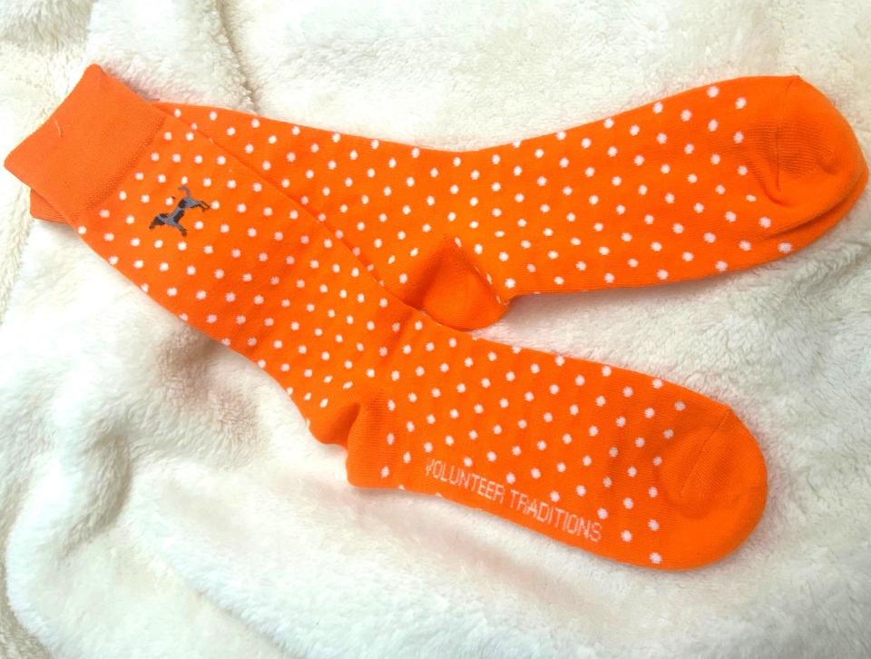 A pair of orange and white polka dotted socks with a bluetick hound on the ankle. It's sold at the Vol Shop.