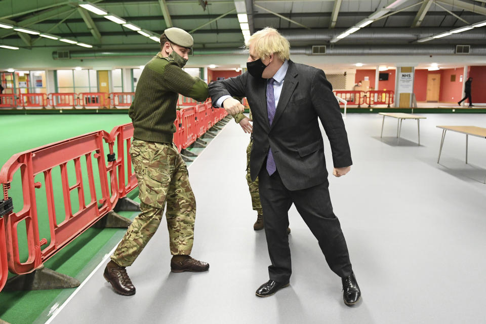 Britain's Prime Minister Boris Johnson elbow bumps a member of the military as he meets troops setting up a vaccination centre in the Castlemilk district of Glasgow, on his one day visit to Scotland, Thursday, Jan. 28, 2021. Johnson is facing accusations that he is not abiding by lockdown rules as he makes a trip to Scotland on Thursday to laud the rapid rollout of coronavirus vaccines across the United Kingdom. (Jeff Mitchell/Pool Photo via AP)