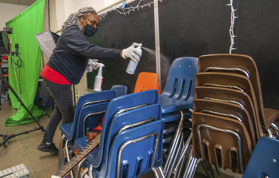 FILE - In this March 4, 2021 file photo, Latisha Bledsoe cleans chairs in the music room at Manchester Academic Charter School, during the coronavirus pandemic, in Pittsburgh. U.S. guidelines that say students should be kept 6 feet apart in schools are receiving new scrutiny from federal health experts, state governments and education officials working to return as many children as possible to the classroom. (Andrew Rush/Pittsburgh Post-Gazette via AP, File)