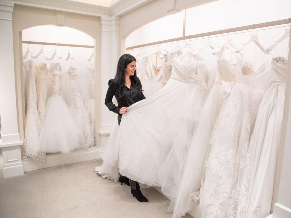 A woman looks at a wedding dress on a hanger at Kleinfeld.