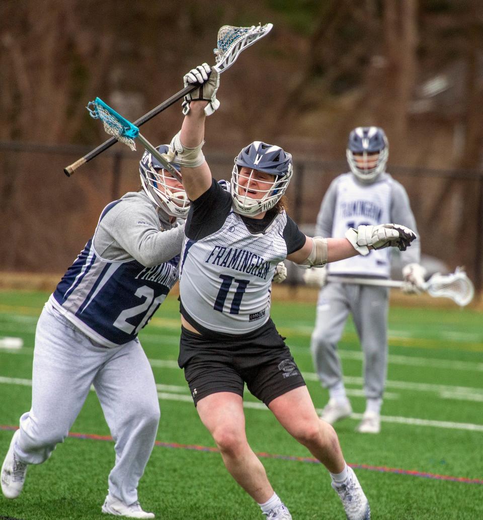 Framingham High School senior lacrosse captain Henry Goldberg (#11) is checked by his twin brother, senior captain Mitch Goldberg, at tryouts on the Fuller Middle School turf fields, March 20, 2024.