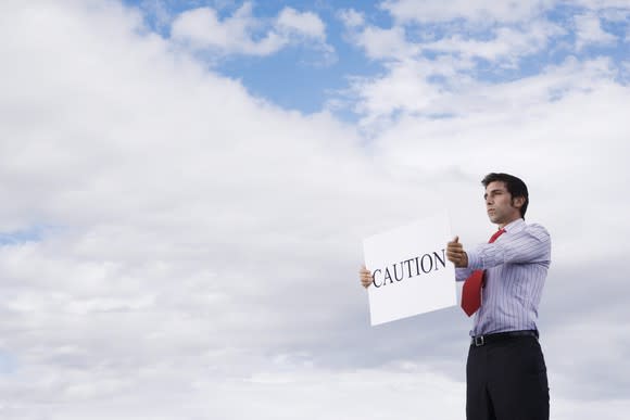 Business man holding a sign that says caution.