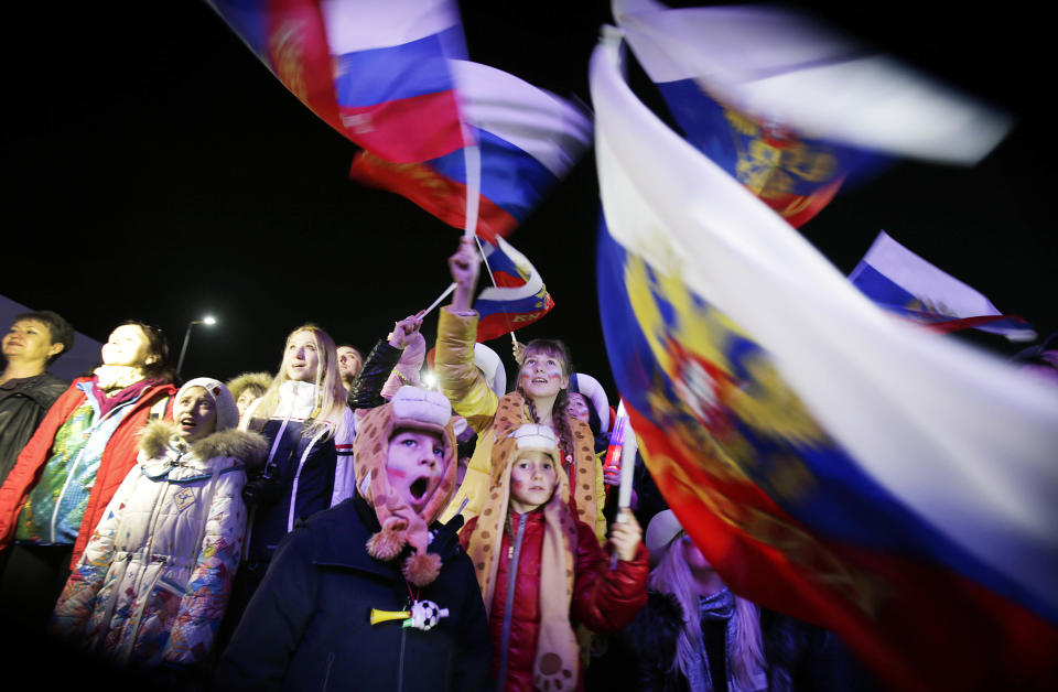 A Russian child yawns while others wave the national flag as the national anthem is being played during the live telecast of the 2014 Winter Olympics opening ceremony, Friday, Feb. 7, 2014, in downtown Sochi, Russia. (AP Photo/Wong Maye-E)