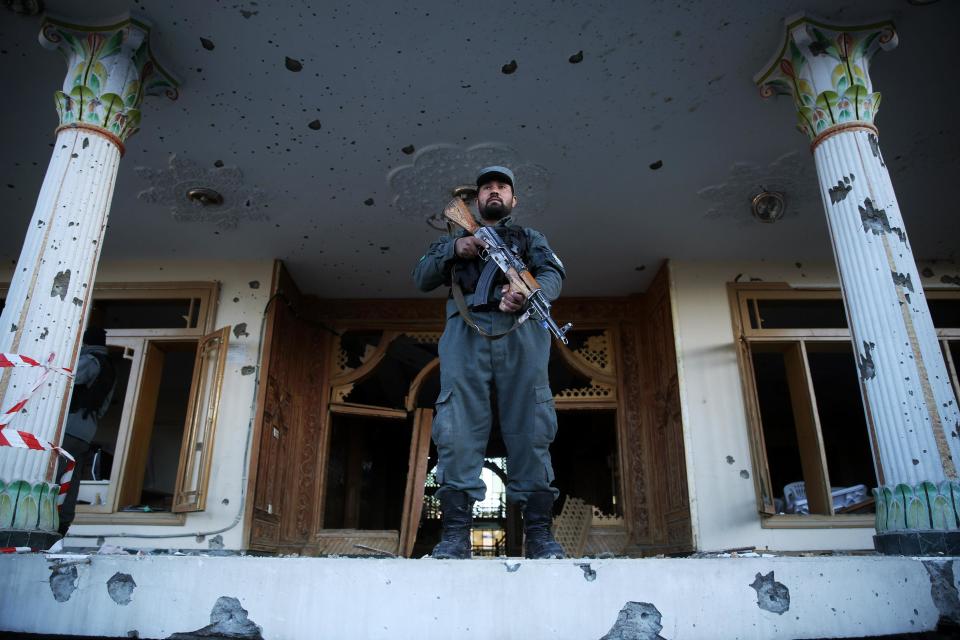 An Afghan policeman stands guard in front of an Independent Elections Commission (IEC) building after a gun battle between security forces and insurgents in Kabul, Afghanistan, Tuesday, March 25, 2014. Gunmen stormed into the building, trapping dozens of employees inside and killing four people. A candidate for a seat on a provincial council was among those killed, along with an election worker, a civilian and a policeman. (AP Photo/Massoud Hossaini)